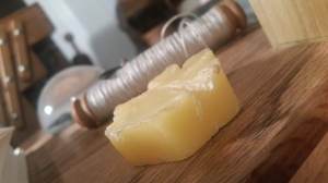 A roll of linen thread in the background with a block of beeswax in the foreground.